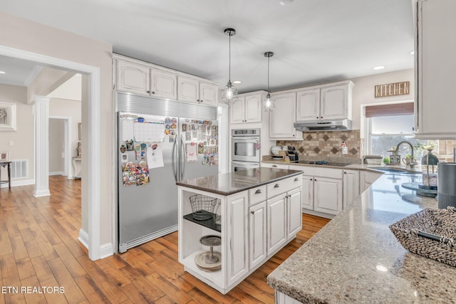 kitchen with stainless steel appliances, under cabinet range hood, white cabinets, and a sink