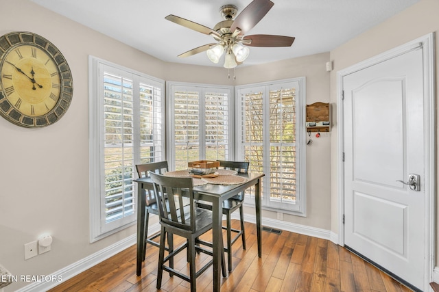 dining room featuring wood finished floors, baseboards, a ceiling fan, and visible vents