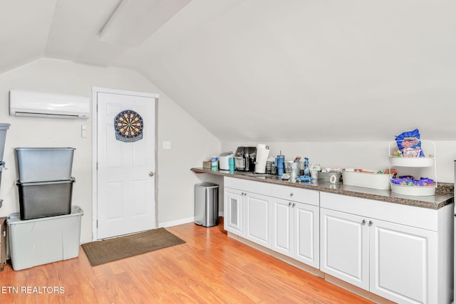 bar with a wall mounted AC, light wood finished floors, and vaulted ceiling