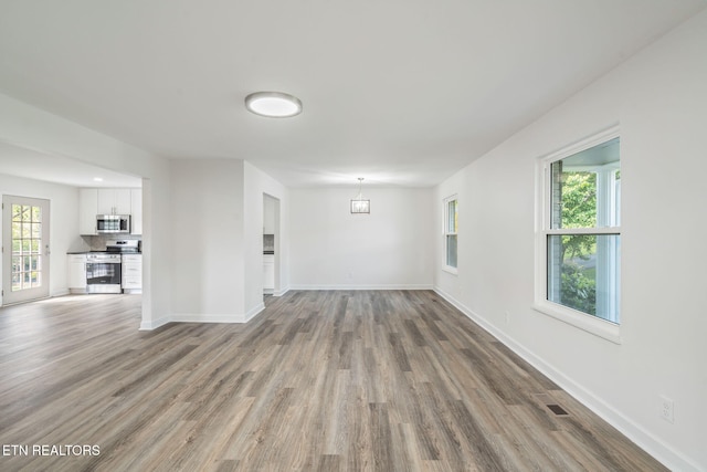 unfurnished room featuring a wealth of natural light, wood finished floors, and baseboards