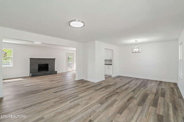 unfurnished living room with a fireplace, baseboards, wood finished floors, and a healthy amount of sunlight