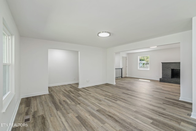 unfurnished living room featuring a fireplace, visible vents, baseboards, and wood finished floors