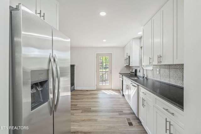 kitchen featuring visible vents, white cabinets, light wood-type flooring, dark countertops, and stainless steel appliances