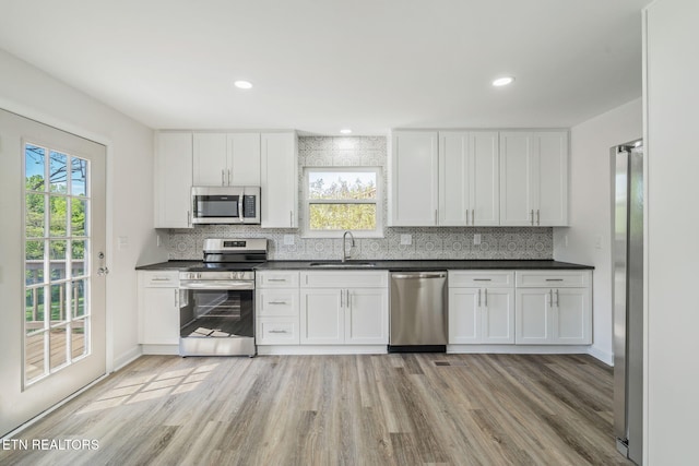 kitchen featuring white cabinetry, a sink, backsplash, and appliances with stainless steel finishes