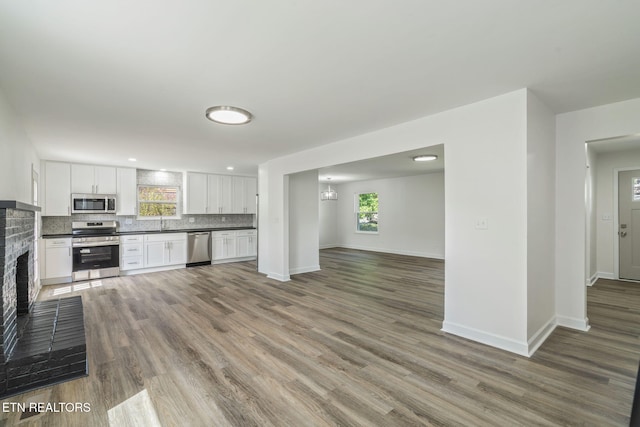 kitchen featuring tasteful backsplash, open floor plan, dark countertops, white cabinetry, and stainless steel appliances