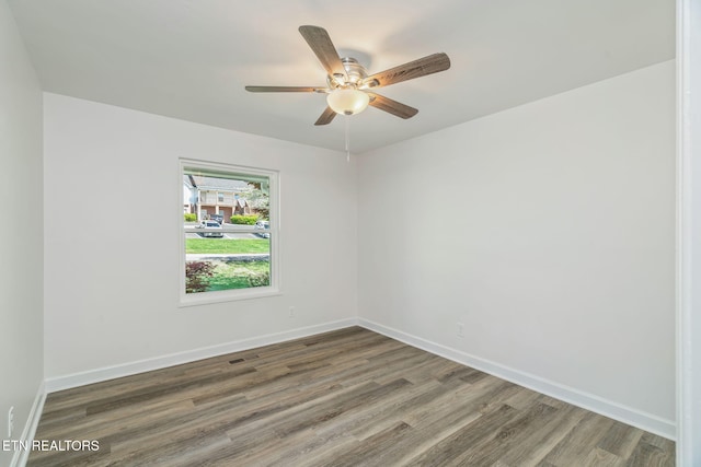 empty room with wood finished floors, baseboards, and a ceiling fan