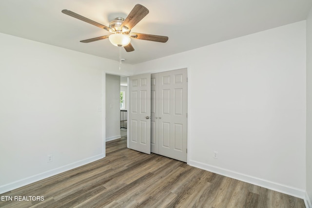 unfurnished bedroom with wood finished floors, baseboards, and a closet