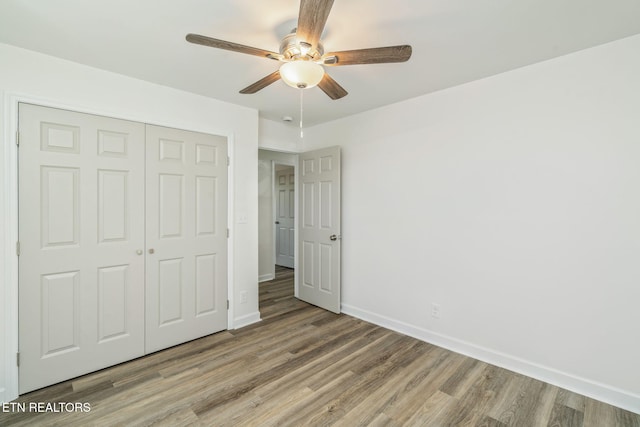 unfurnished bedroom featuring a closet, light wood-style floors, baseboards, and a ceiling fan