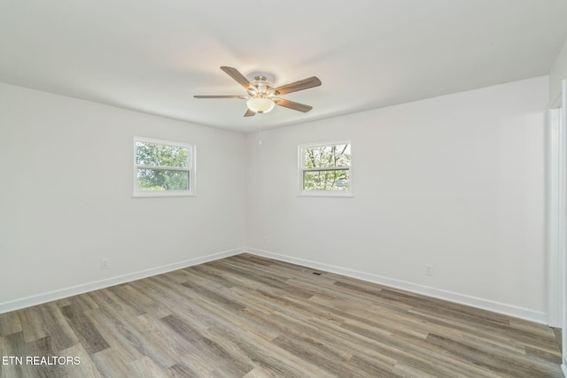 spare room with light wood-style flooring, ceiling fan, baseboards, and a wealth of natural light