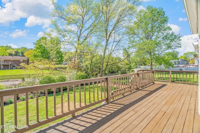 wooden terrace featuring a yard and fence