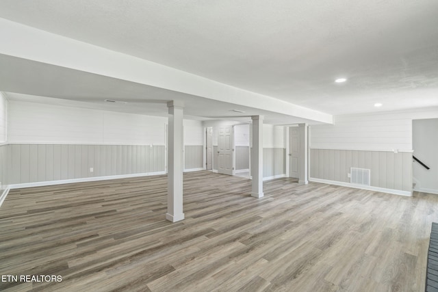 finished basement featuring baseboards, recessed lighting, wainscoting, visible vents, and wood finished floors