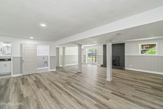 basement featuring wood finished floors, a fireplace, a sink, and baseboards