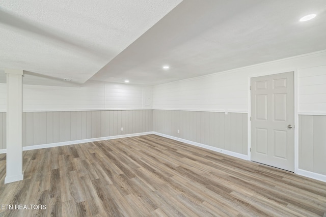 finished basement with baseboards, wood finished floors, and a textured ceiling