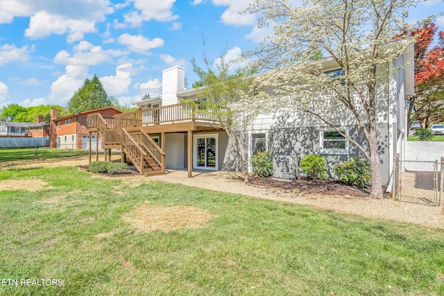 rear view of house with a lawn, fence, stairs, a chimney, and a deck