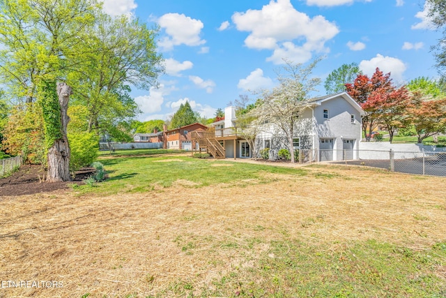 view of yard featuring fence, a wooden deck, a garage, and stairs