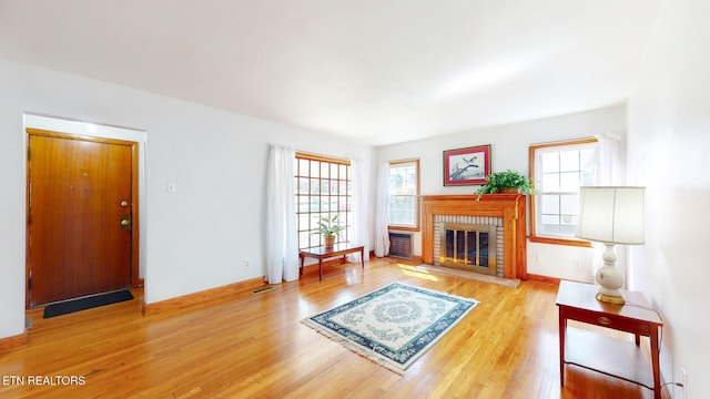 living room with visible vents, a brick fireplace, wood finished floors, and a wall mounted AC