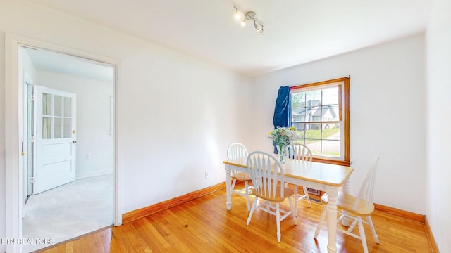 dining space with track lighting, baseboards, and light wood-type flooring