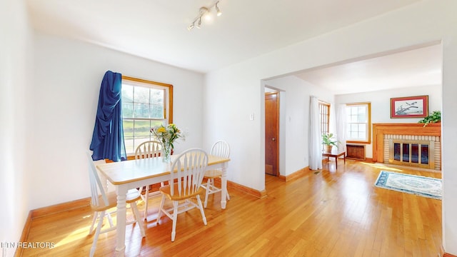 dining space featuring track lighting, baseboards, a wealth of natural light, and light wood-style flooring