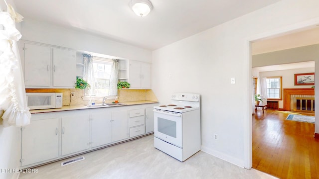 kitchen with open shelves, a sink, white appliances, light countertops, and visible vents