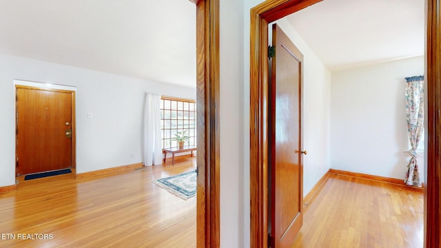 hallway featuring light wood-type flooring and baseboards