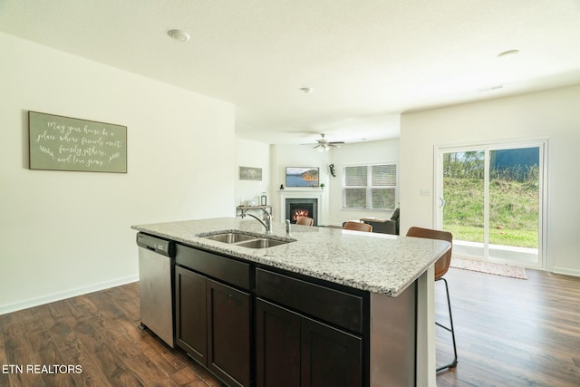 1133 Beacon Rd, Sevierville, TN 37876 - kitchen featuring a sink, dark wood-style flooring, a warm lit fireplace, stainless steel dishwasher, and light stone counters
