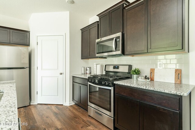 1133 Beacon Rd, Sevierville, TN 37876 - kitchen with appliances with stainless steel finishes, dark brown cabinets, light stone countertops, dark wood-type flooring, and decorative backsplash