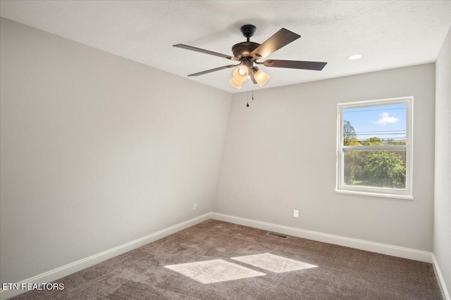 carpeted spare room with ceiling fan, baseboards, and visible vents