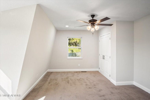 carpeted spare room featuring baseboards and ceiling fan