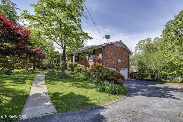 view of home's exterior featuring a garage, a lawn, driveway, and brick siding