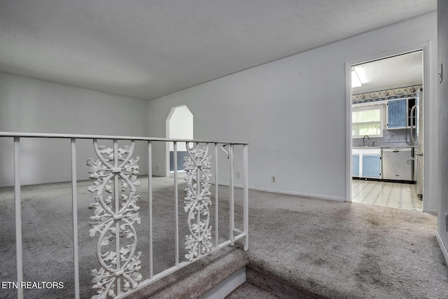 corridor with carpet floors, a sink, and baseboards