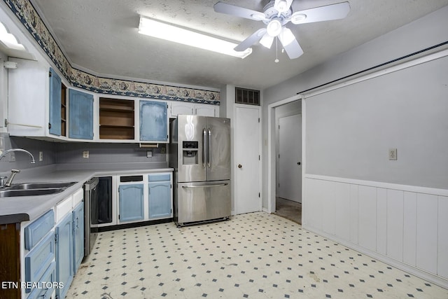 kitchen featuring a ceiling fan, open shelves, a sink, a wainscoted wall, and stainless steel appliances