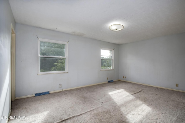 empty room featuring visible vents, carpet flooring, and baseboards
