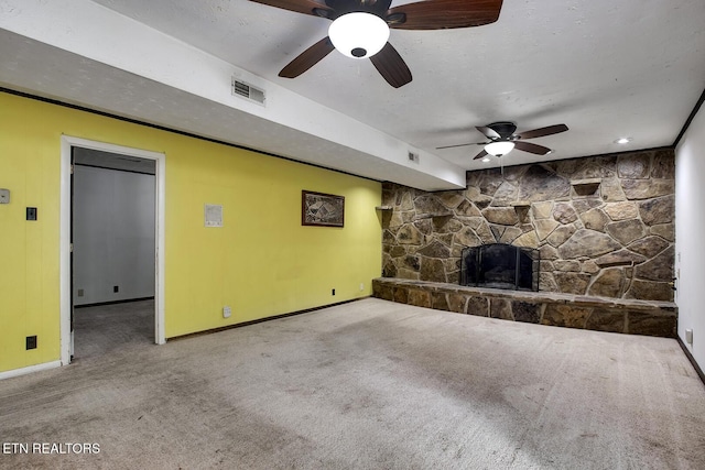 unfurnished living room featuring ceiling fan, a stone fireplace, visible vents, baseboards, and carpet floors