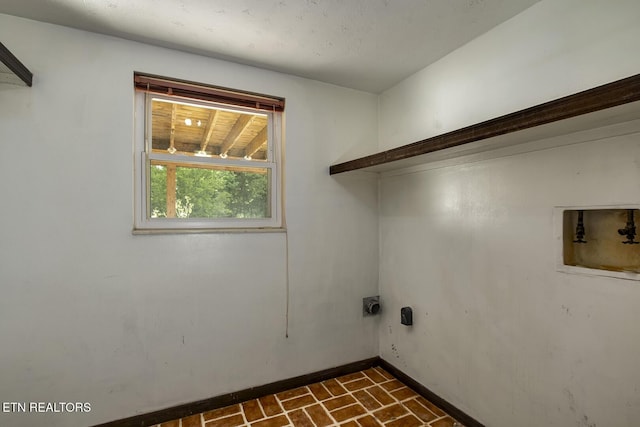 clothes washing area with laundry area, baseboards, hookup for a washing machine, brick floor, and hookup for an electric dryer