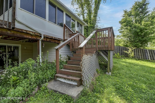 exterior space with fence, a lawn, a sunroom, and stairway