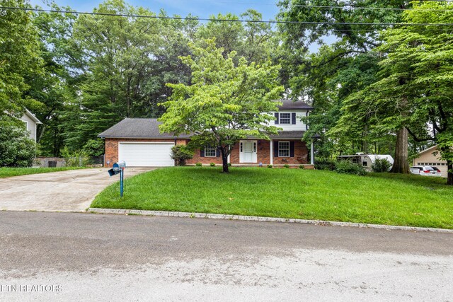 1104 Burning Tree Ln, Knoxville, TN 37923 - view of front facade with driveway, a garage, a front yard, brick siding, and view of wooded area