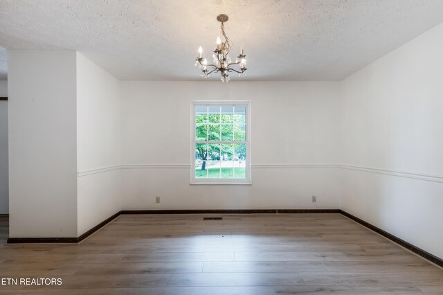 1104 Burning Tree Ln, Knoxville, TN 37923 - unfurnished room featuring a chandelier, a textured ceiling, wood finished floors, and baseboards