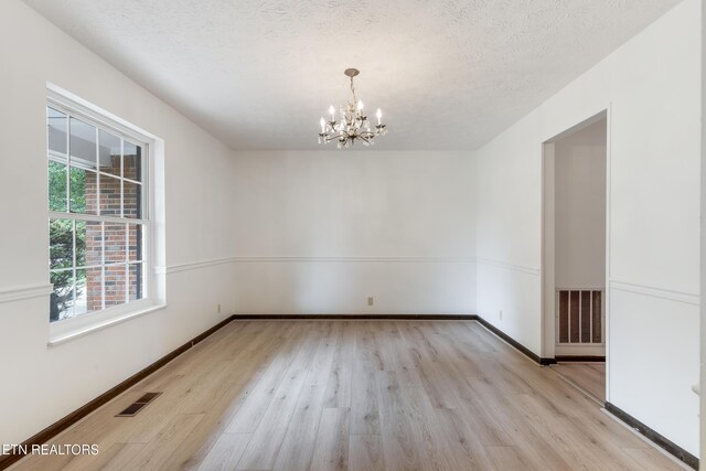 1104 Burning Tree Ln, Knoxville, TN 37923 - spare room featuring a chandelier, wood finished floors, baseboards, and a textured ceiling