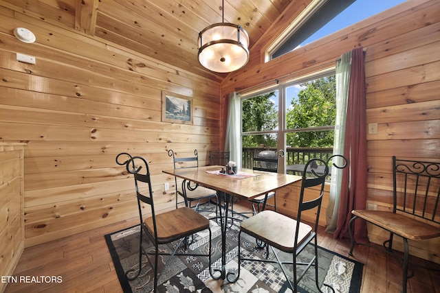 dining room with wood walls, hardwood / wood-style floors, vaulted ceiling, and wooden ceiling