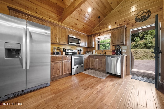 kitchen featuring stainless steel appliances, light wood-style floors, brown cabinets, vaulted ceiling, and pendant lighting