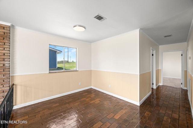 spare room featuring brick floor, baseboards, wainscoting, and visible vents