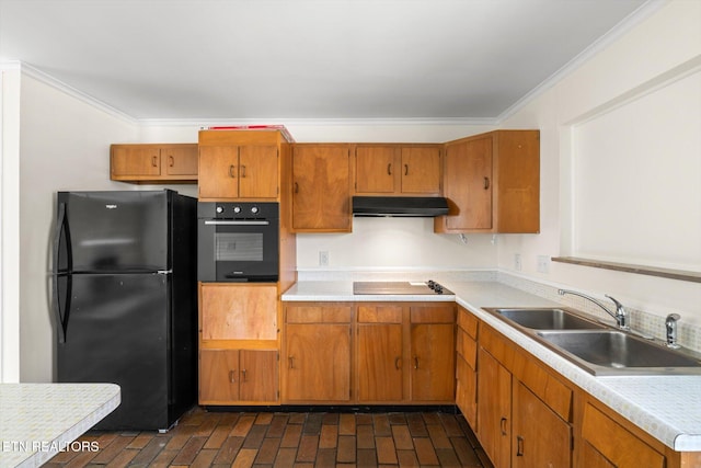 kitchen featuring black appliances, under cabinet range hood, light countertops, a sink, and brick floor
