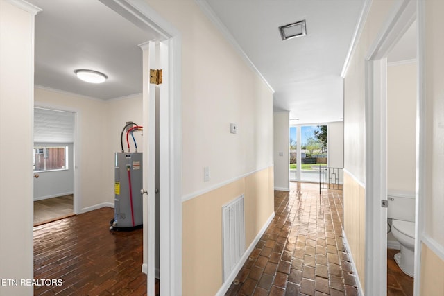 hall featuring brick floor, crown molding, visible vents, and water heater
