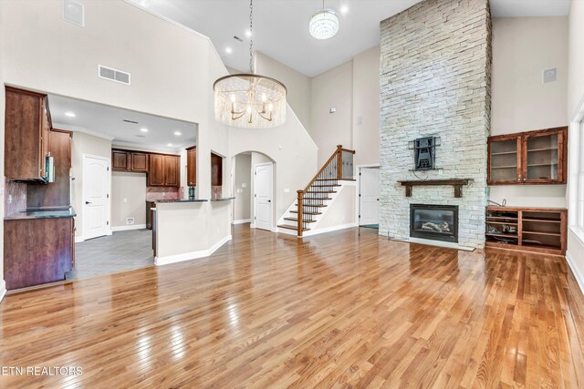 10033 Autumn Valley Ln, Knoxville, TN 37922 - unfurnished living room with a fireplace, light wood-type flooring, visible vents, stairway, and a high ceiling