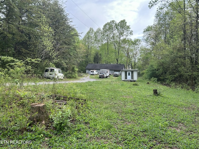 view of yard with a wooded view and an outbuilding