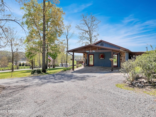 view of front facade with a carport, stone siding, and driveway