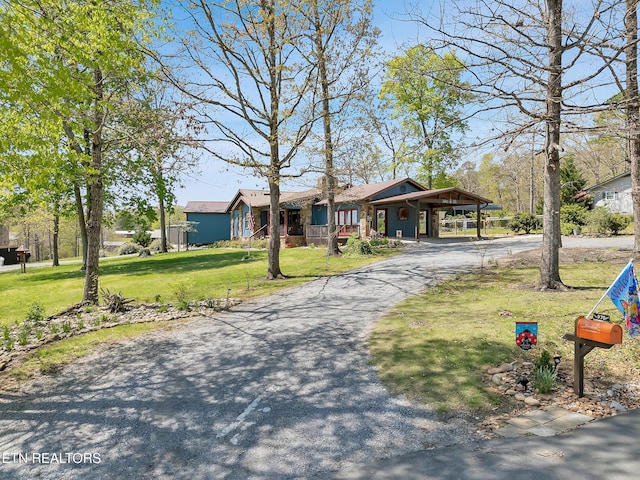 ranch-style home featuring aphalt driveway, a carport, and a front lawn
