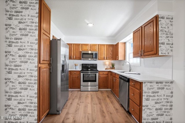 kitchen with brown cabinets, light countertops, appliances with stainless steel finishes, and light wood-style floors