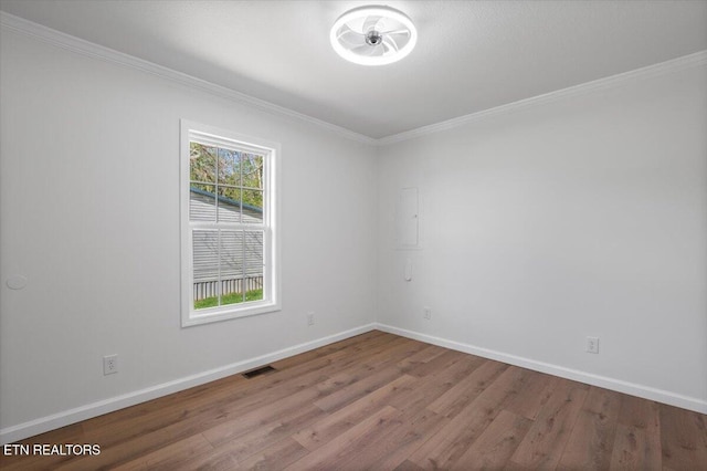 unfurnished room with visible vents, ornamental molding, baseboards, and wood finished floors