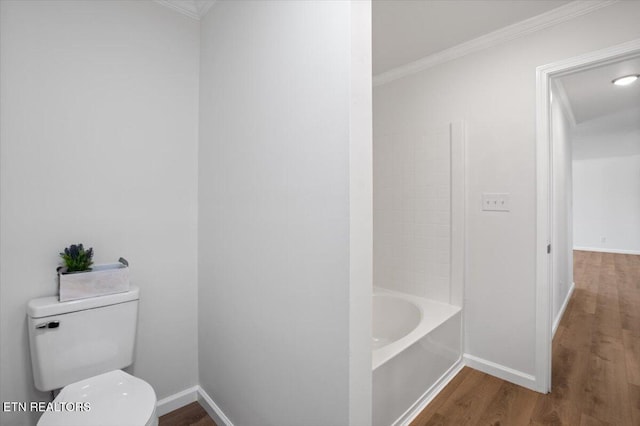 full bath with a bathtub, ornamental molding, toilet, and wood finished floors